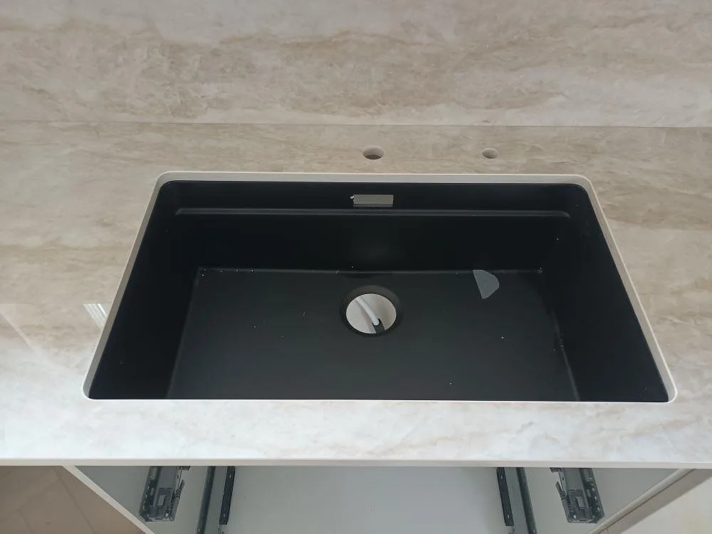 Polerad Dekton Arga köksbänkskiva i keramik med underlimmad svart diskho och väggbeklädnad i Norrtälje.
