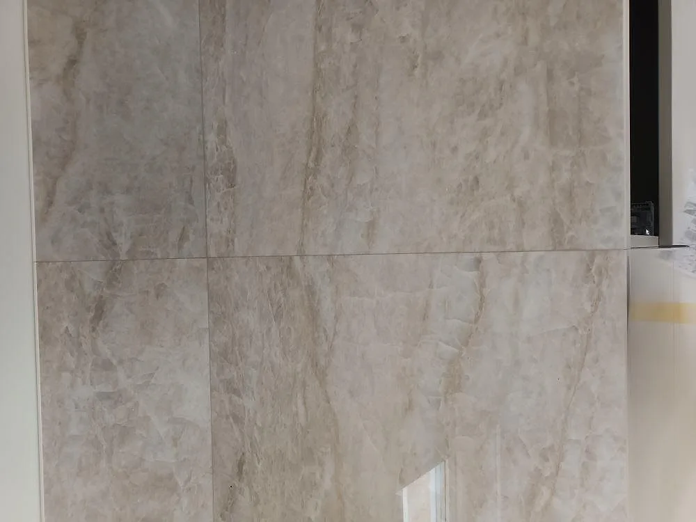 Väggbeklädnad i polerad Dekton Arga keramik med beigegrå ådring i ett kök i Norrtälje.
