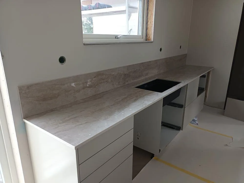 Köksbänkskiva i polerad Dekton Arga keramik med svart diskho och matchande stänkskydd i ett kök i Norrtälje.