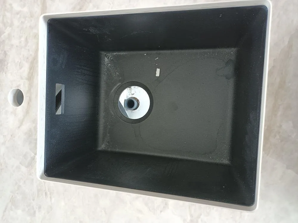 Närbild ovanifrån på svart diskho monterad i polerad Dekton Arga keramikbänkskiva i kök i Norrtälje.