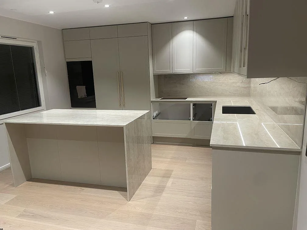 Dekton Arga köksbänkskiva i kök i Norsborg med svart underlimmad diskho och urtag för induktionshäll, sett över köksön.