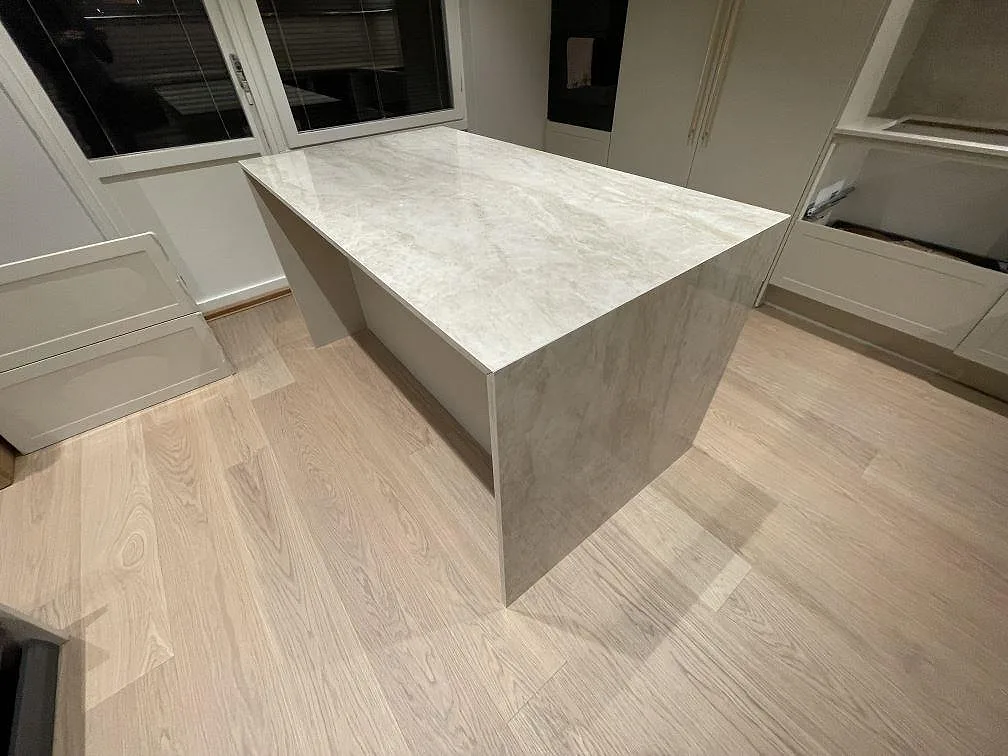 Köksö i polerad Dekton Arga med mjuk ljus ådring i ett kök i Norsborg.