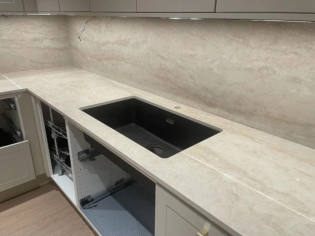 Närbild på svart underlimmad kompositdiskho i polerad Dekton Arga bänkskiva med stänkvägg i sten i Norsborg.
