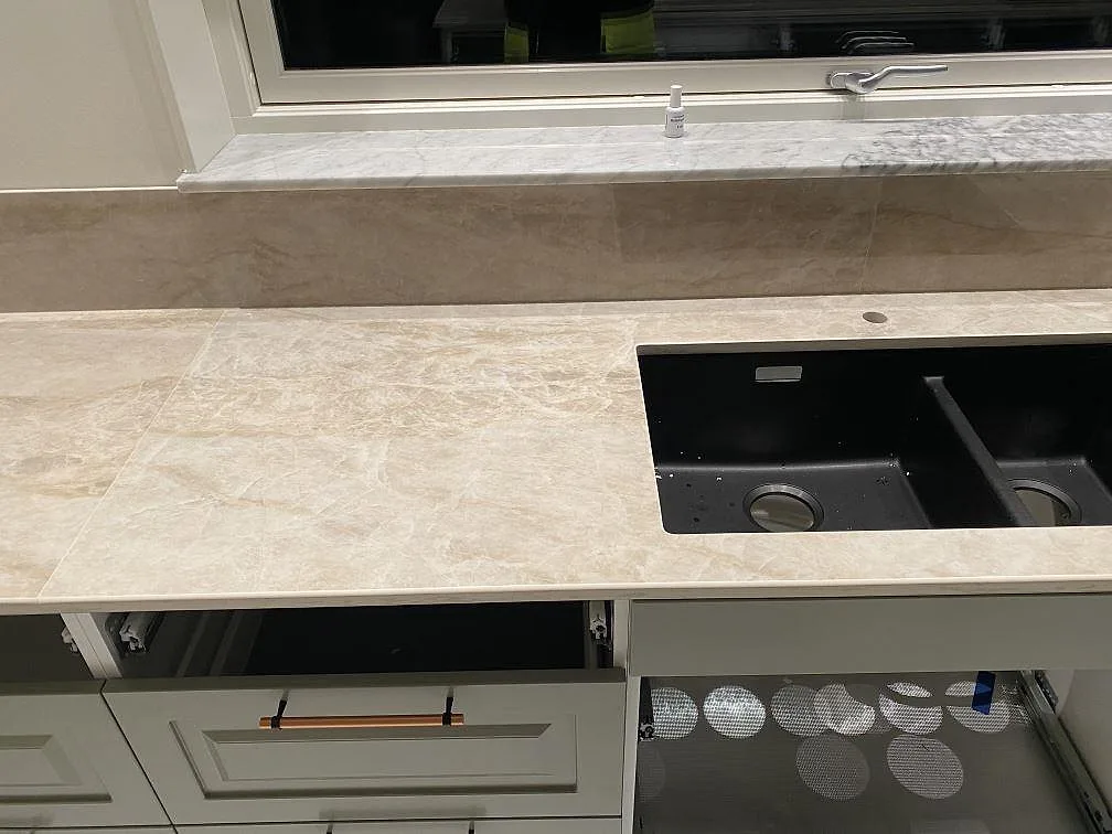 Översiktsbild av kök i Nybro med köksö och bänkrad i Dekton Arga, urfräsningar för häll och diskhoar under montering.