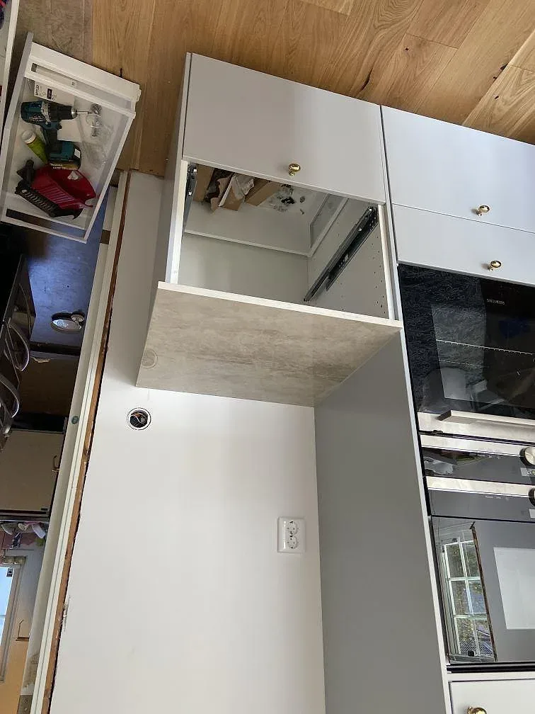 Infälld induktionshäll i en köksbänkskiva av Dekton Arga med mjuk grå ådring i ett kök i Öjersjö.