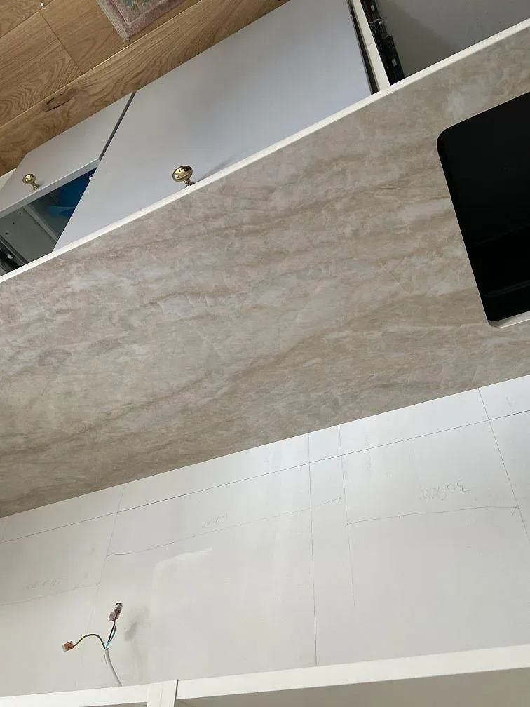 Köksbänkskiva i matt Dekton Arga längs väggen under montering i ett kök i Öjersjö.