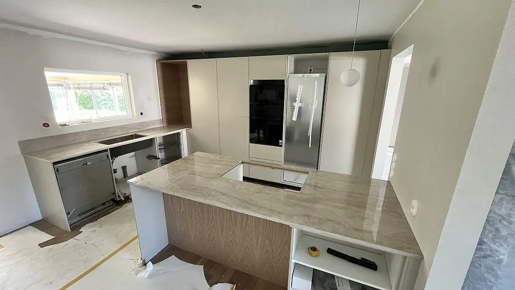 Köksbänkskiva och köksö i polerad Dekton Arga keramik, 20 mm, med hällurtag och diskzon i ett kök under montering i Örebro.