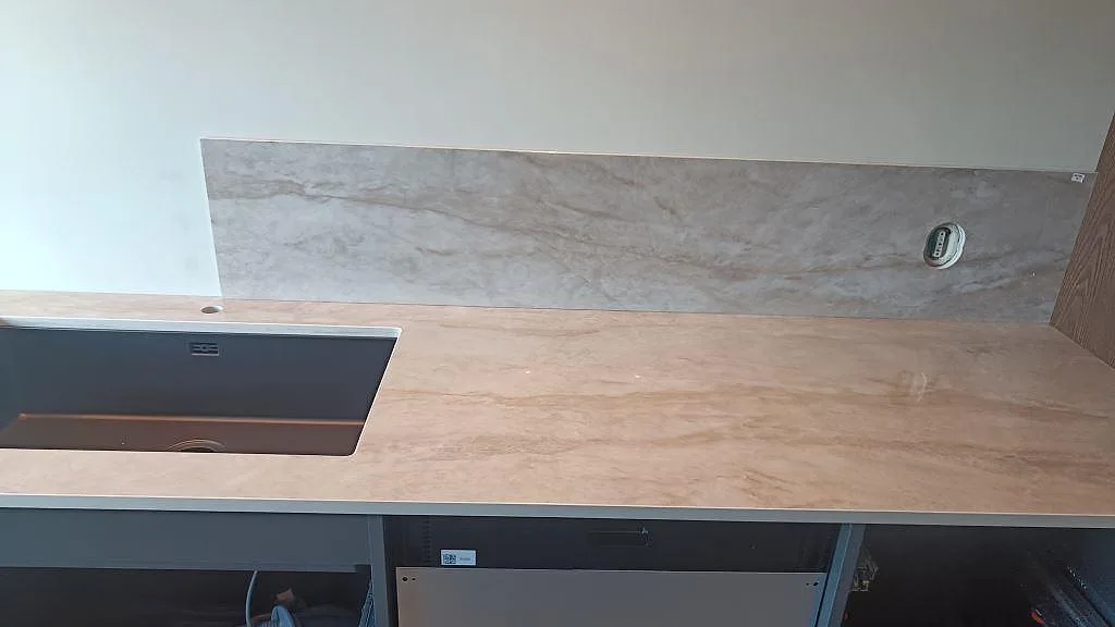 Köksbänkskiva i polerad Dekton Arga med underlimmad diskho och 8 mm stänkskydd i ett kök i Påarp.