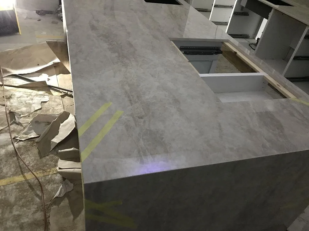 Köksbänkskiva och köksö i polerad Dekton Arga, ljust gråbeige keramik, monterad i ett kök under installation i Partille.
