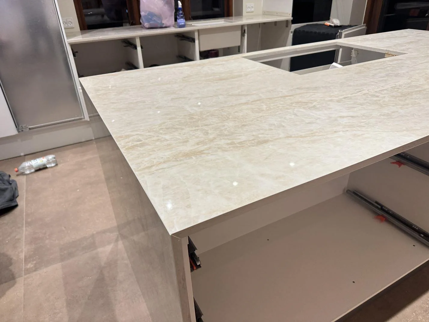 Stor köksbänkskiva i polerad Dekton Arga med blank yta och öppna köksstommar under montering i Roskilde.