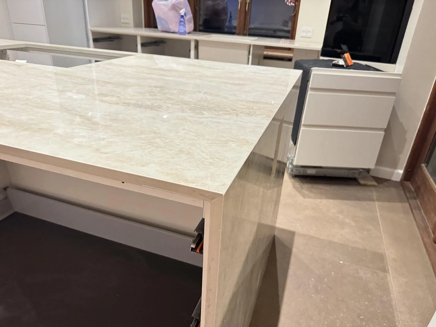 Detalj av bänkkant och sidopanel i polerad Dekton Arga på köksö under montering i Roskilde.