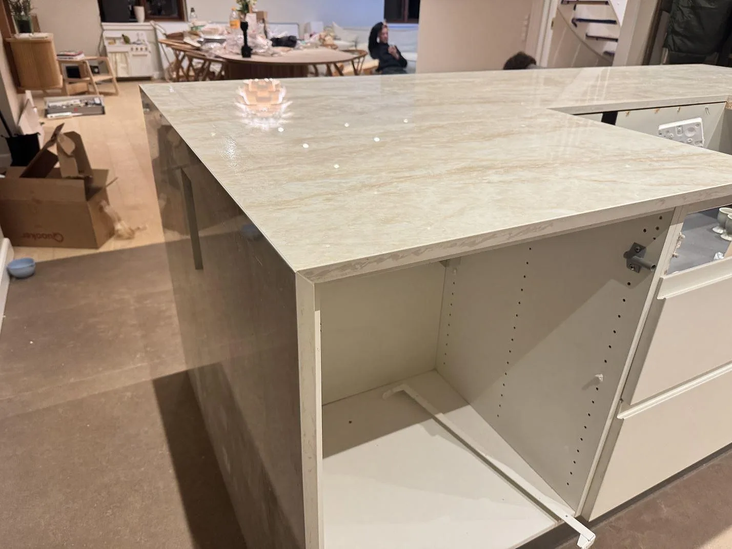 Bred vy över köksö i polerad keramisk Dekton Arga med ljus ådring och öppna skåpstommar i Roskilde.