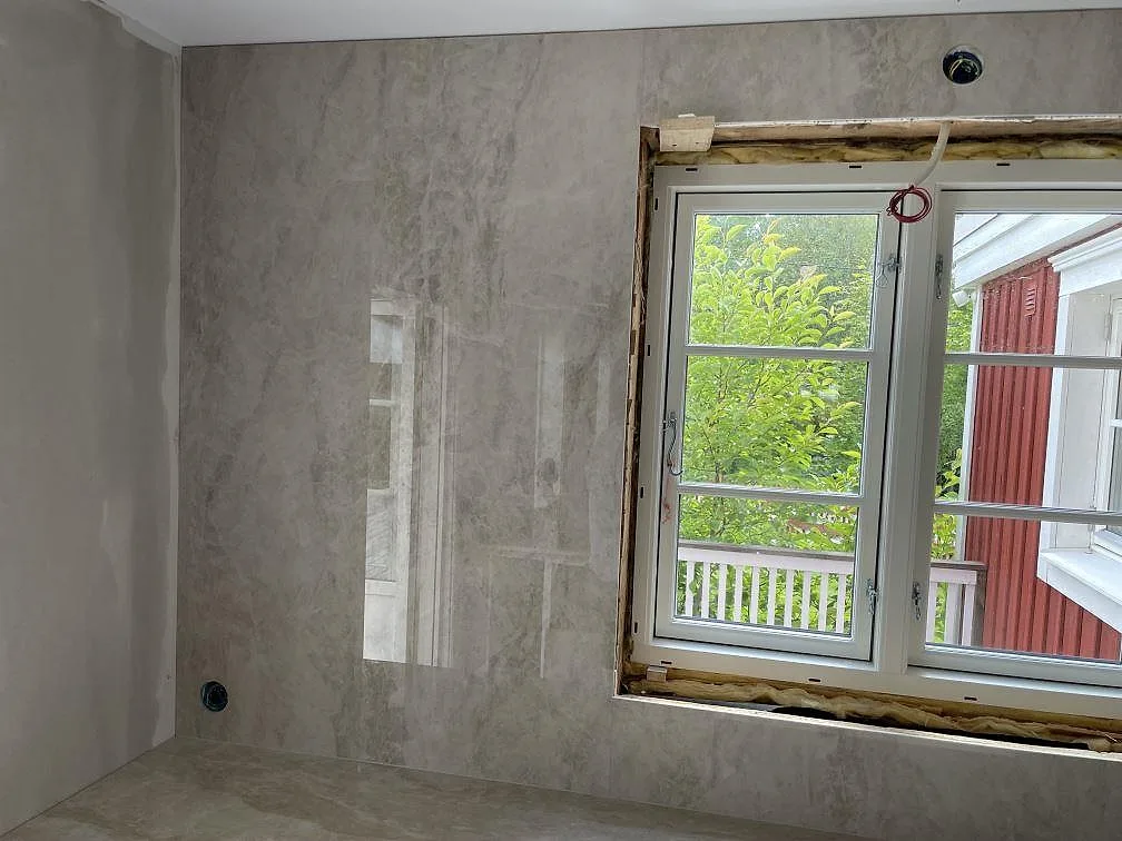 Närbild på polerad Dekton Arga som väggbeklädnad och bänkskiva vid fönster i ett kök i Sandviken.