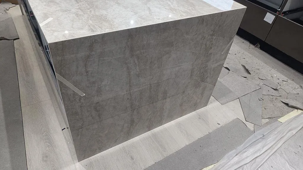 Neddragen gavel på köksö i polerad Dekton Arga med marmorerat mönster och mörka köksstommar i Sengeløse.
