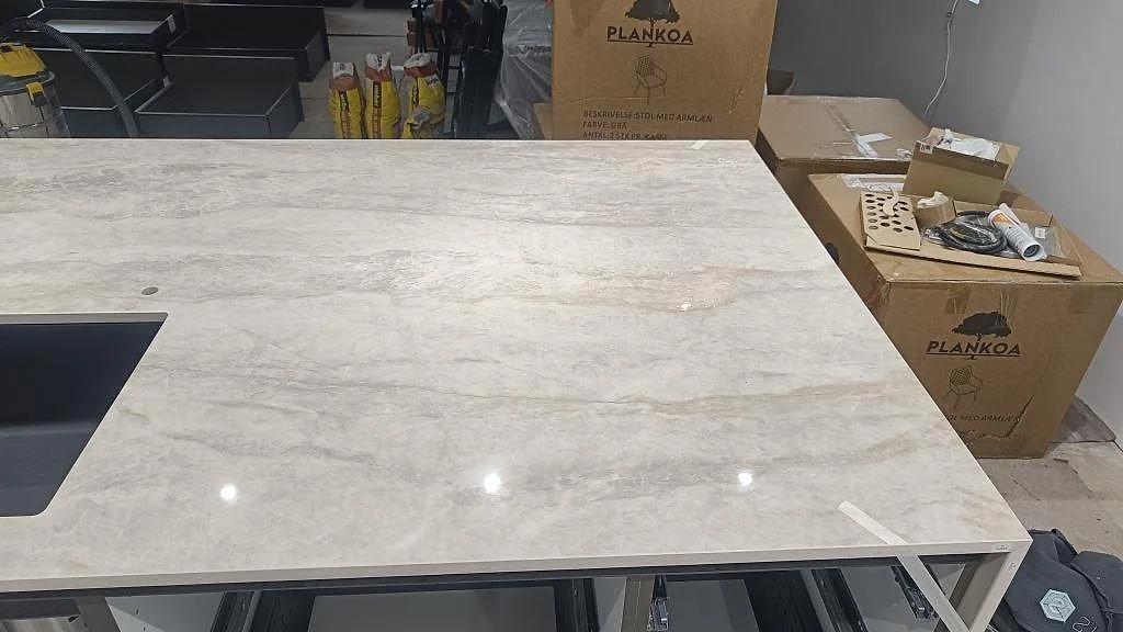 Stor köksö i Dekton Arga med polerad yta, diskho i kanten och monteringsmaterial runt köket i Sengeløse.