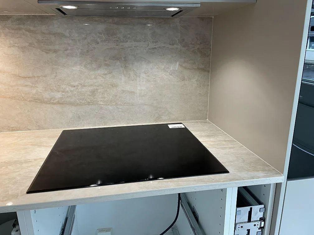 Svart häll monterad i polerad Dekton Arga med stenklädd vägg bakom arbetsytan i Skövde.
