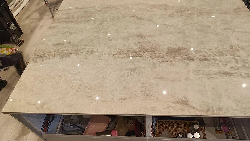 Närbild av den polerade Dekton Arga-ytan på köksön med öppna lådstommar i ett kök i Skövde.
