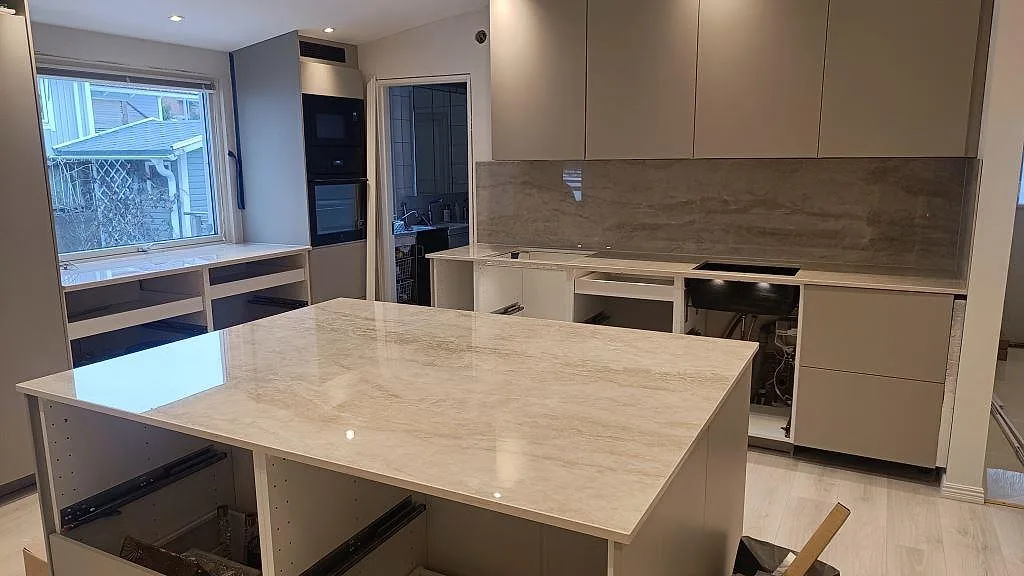 Köksbänkskiva i polerad Dekton Arga, 20 mm, med stor fristående köksö och matchande stänkskydd i ett kök i Skövde.