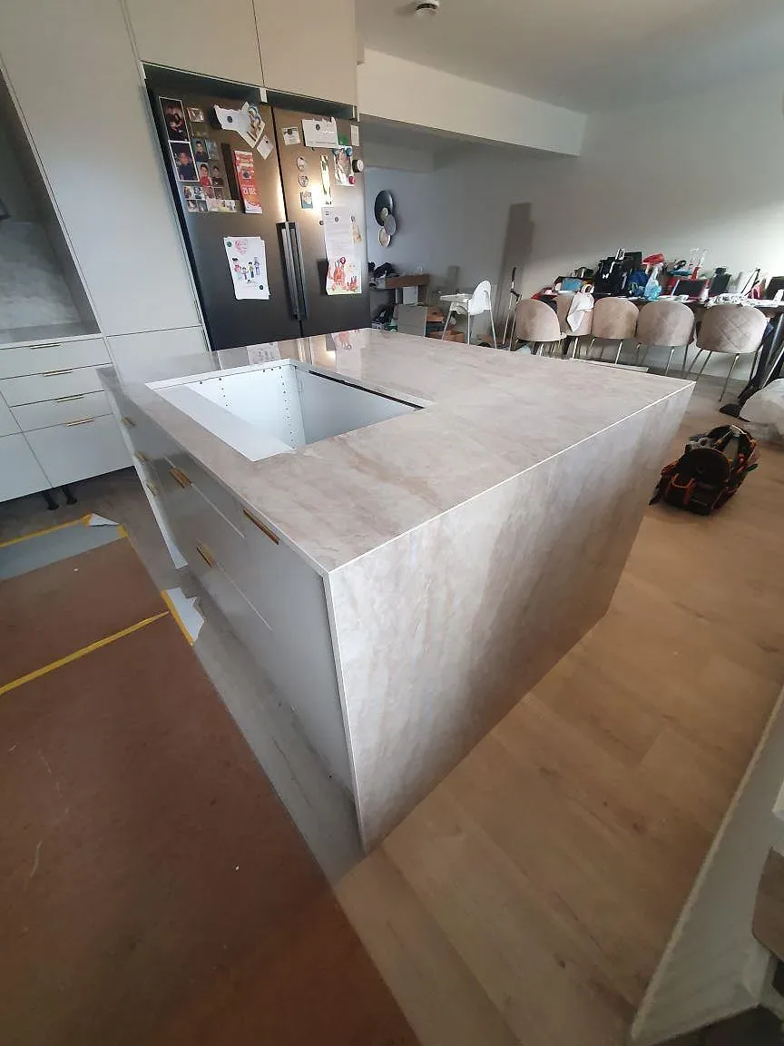 Sidovy av köksö i polerad Dekton Arga keramik med ljus ådring och öppet hällurtag i Söderby.