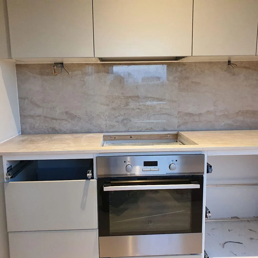 Närbild på polerad Dekton Arga som köksbänkskiva och väggskiva med hällöppning över ugnen i Sollentuna.