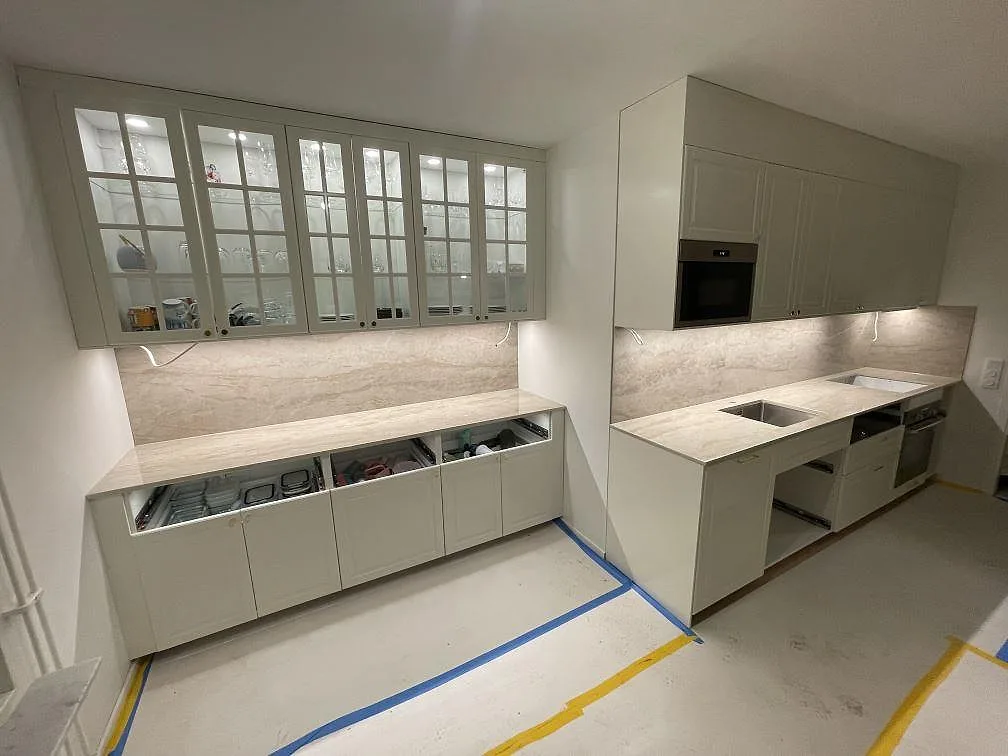 Kök i Solna med köksbänkskiva och låg bufférad i Dekton Arga under glasvitrinskåp, fotat under montering.