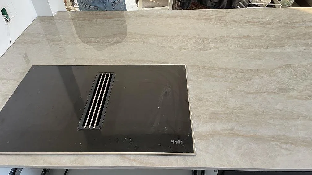 Närbild på polerad Dekton Arga som köksbänkskiva med svart häll och ljus ådring i Solrød.