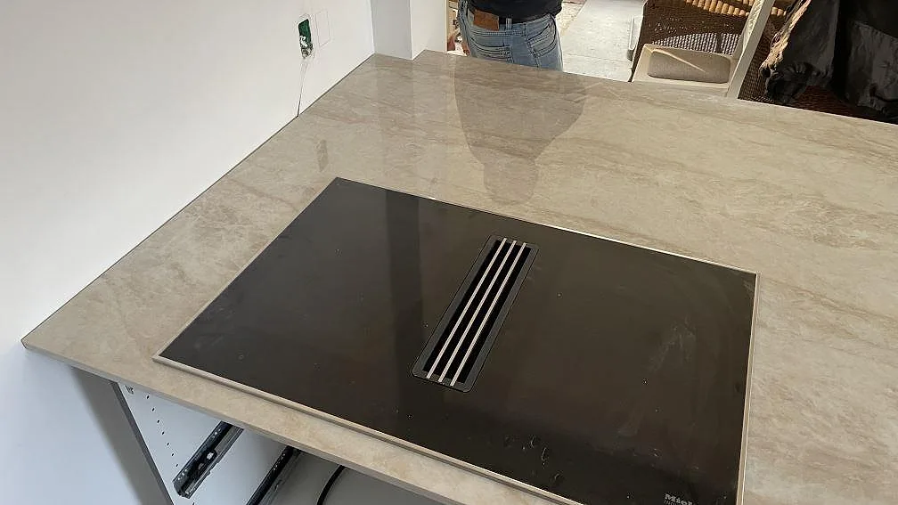 Polerad köksbänkskiva i Dekton Arga med svart häll mot vit vägg i köket i Solrød.