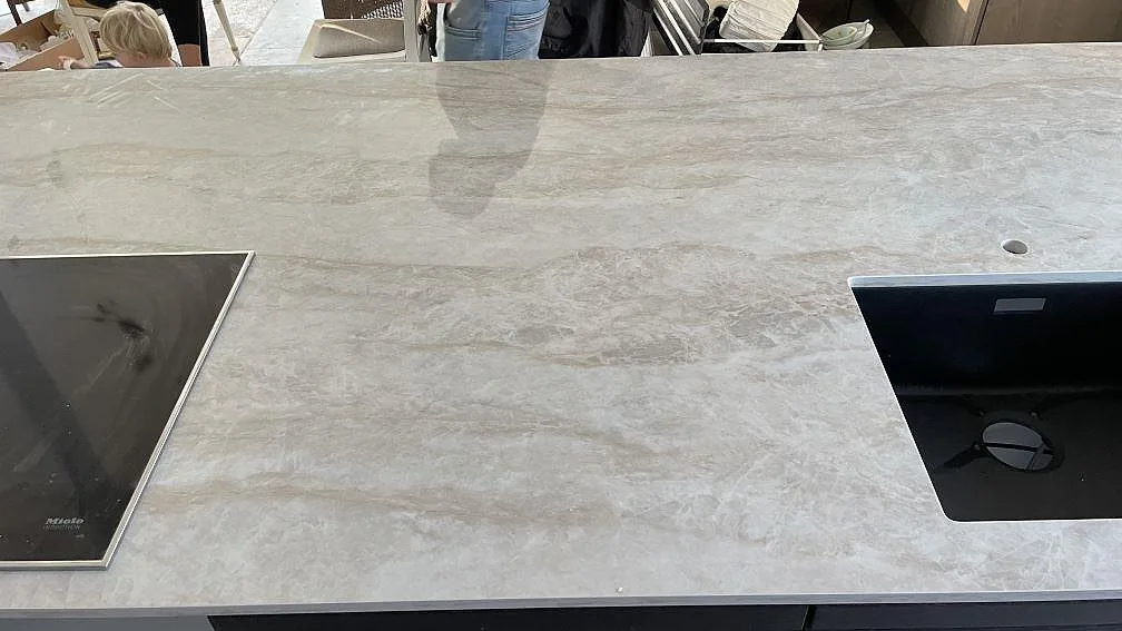 Polerad köksbänkskiva i Dekton Arga med synlig ådring, svart häll och svart diskho i Solrød.