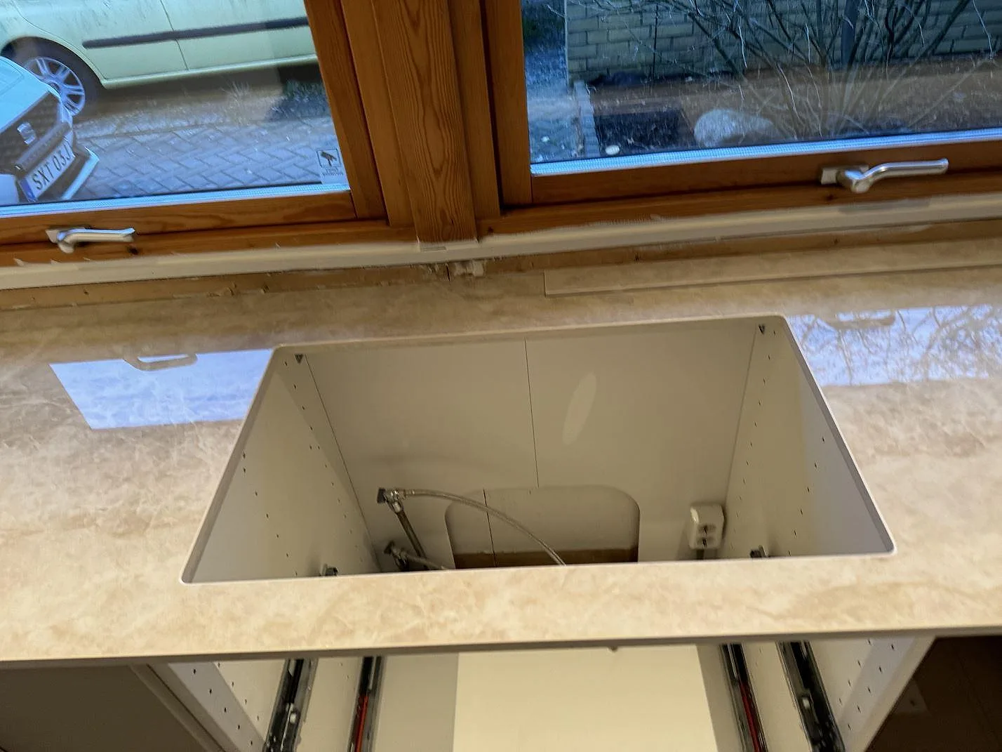 Detalj av polerad Dekton Arga med utskärning vid diskbänksdelen och öppna lådstommar i Staffanstorp.