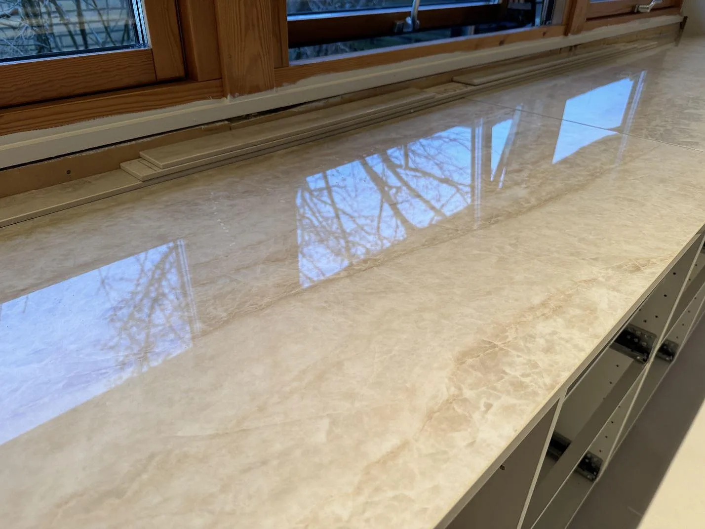 Ytdetalj av polerad Dekton Arga med ljus ådring och fönsterreflexer på köksbänkskivan i Staffanstorp.
