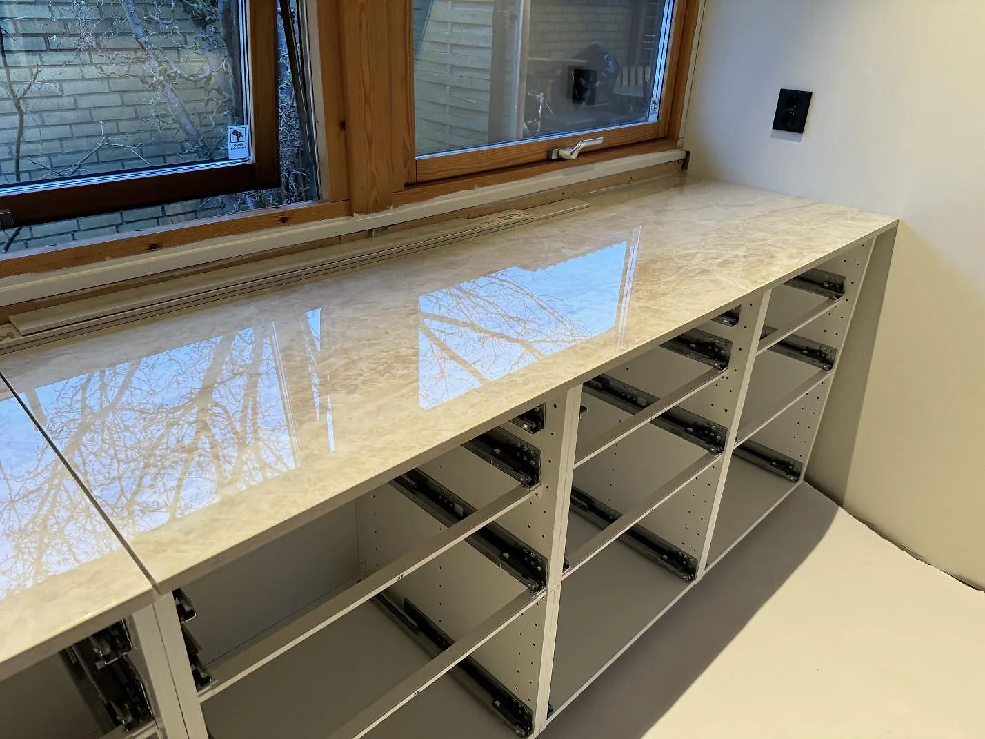 Polerad Dekton Arga som lång bänkskiva över öppna köksstommar vid fönsterparti i Staffanstorp.