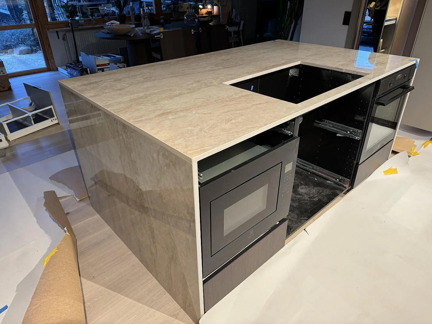 Köksö i polerad Dekton Arga med ugn, hällöppning och vattenfallsida under montering i Staffanstorp.