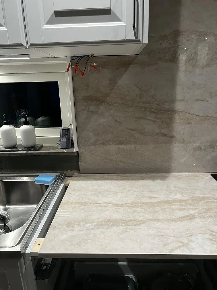 Detalj av polerad Dekton Arga med underlimmad rostfri diskho, arbetsyta och väggbeklädnad i kök i Stenkullen.