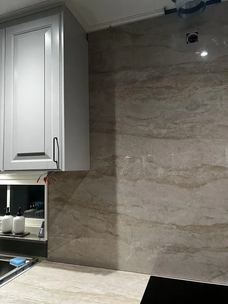 Väggbeklädnad och stänkvägg i polerad Dekton Arga bakom köksbänken med häll och diskho i Stenkullen.