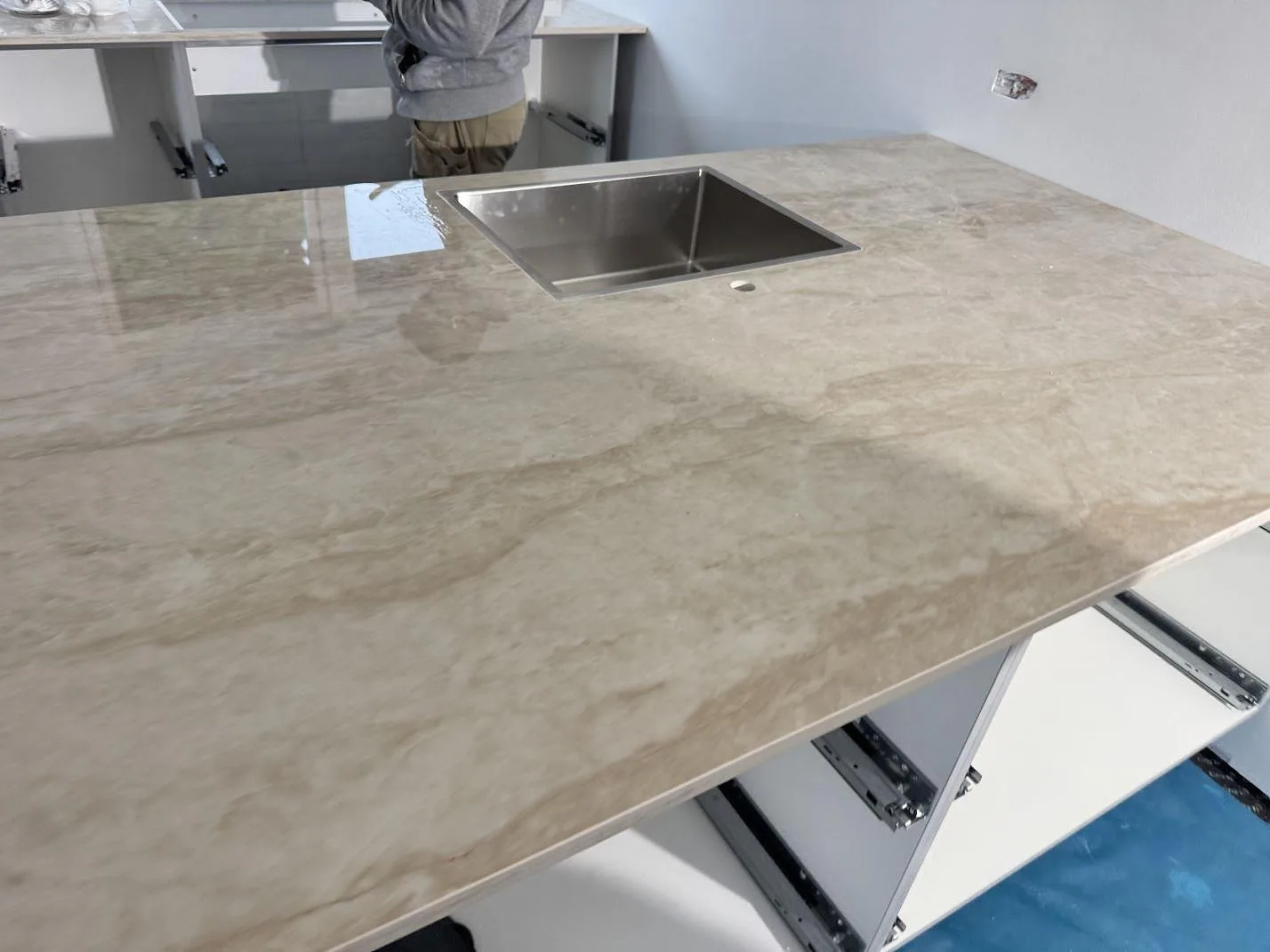 Köksbänkskiva i polerad krämbeige Dekton Arga keramik på en fristående köksö med centrerad underlimmad rostfri diskho i ett kök i Stenløse.