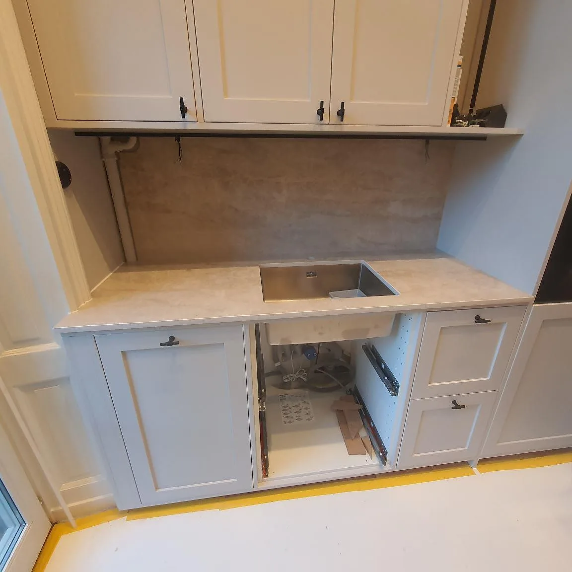 Köksbänkskiva i ljus Dekton Arga keramik, polerad, med underlimmad rostfri diskho och uppvikt stänkskydd i ett kök i Stockholm.