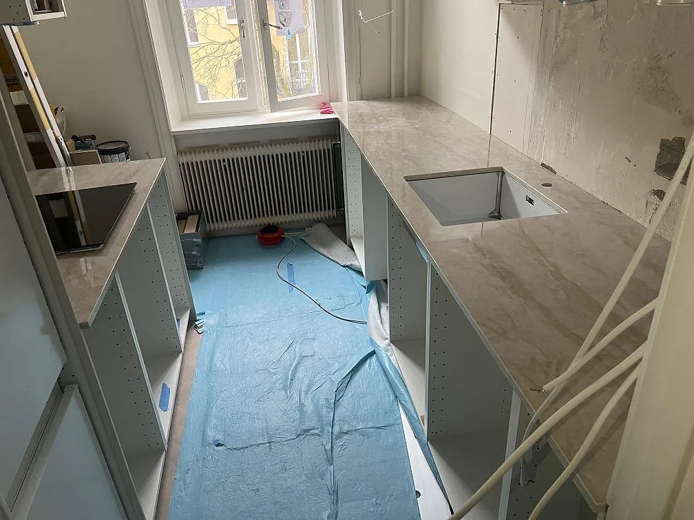 Polerad köksbänkskiva i 20 mm Dekton Arga med diskhourtag och hällurtag i ett U-format kök under montering i Stockholm.