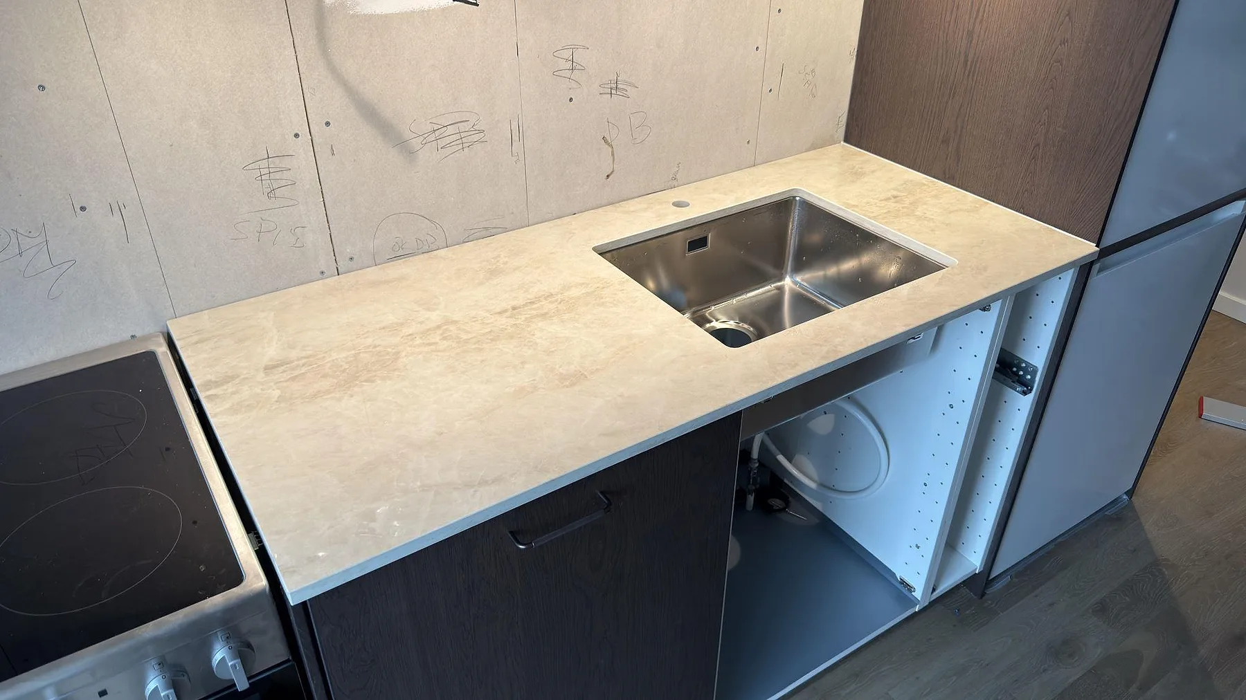 Underlimmad rostfri diskho i en polerad Dekton Arga bänkskiva med krämbeige ådring i ett kök i Stockholm.