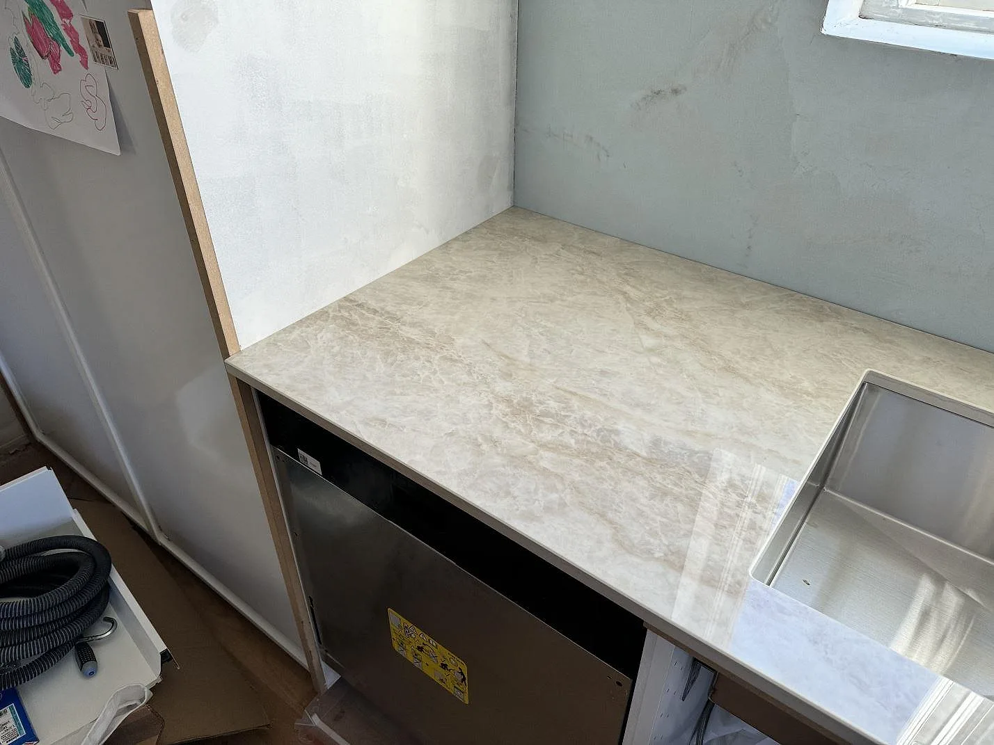 Detalj av polerad Dekton Arga vid diskbänken med rostfri diskho och öppen köksstomme under montering i Svedala.