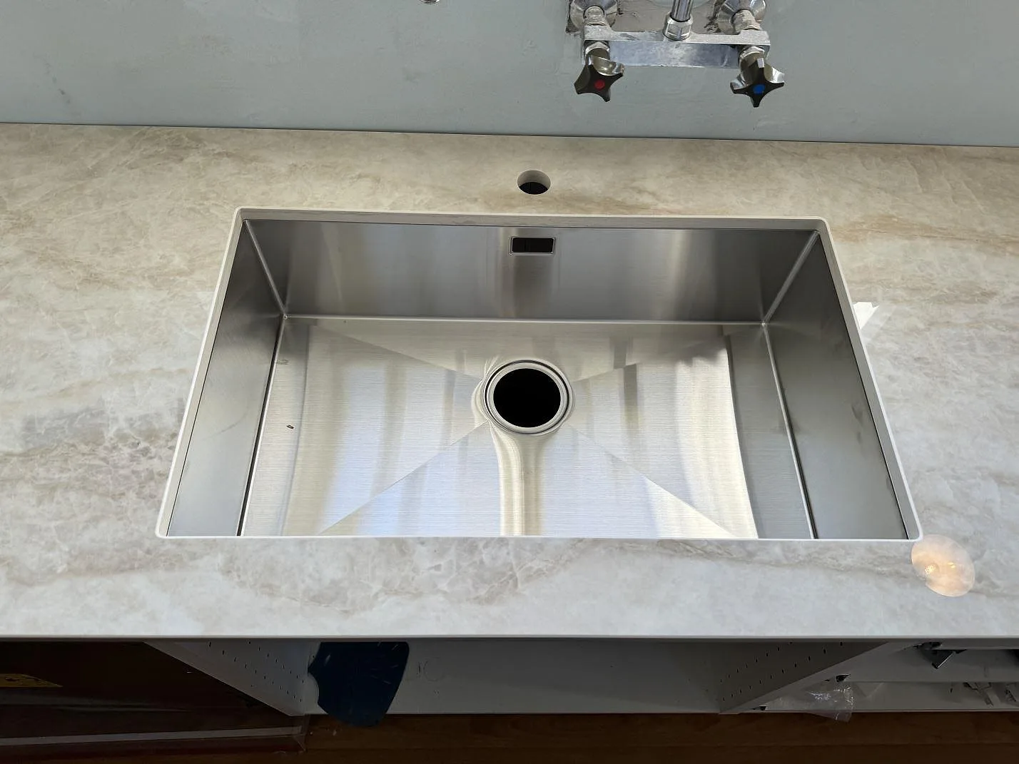 Rostfri diskho i köksbänkskiva av polerad Dekton Arga med kranhål och ljus marmorliknande ådring i Svedala.