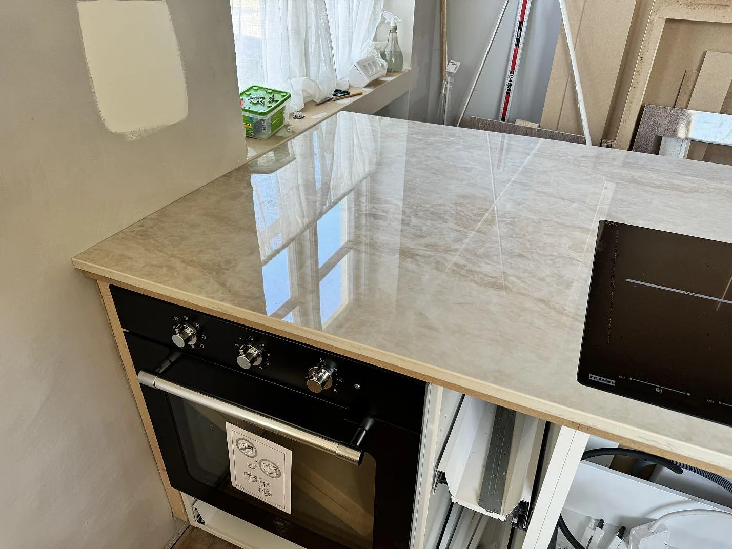 Köksö i polerad Dekton Arga, 20 mm, med häll och ugn monterade i ett kök under arbete i Svedala.