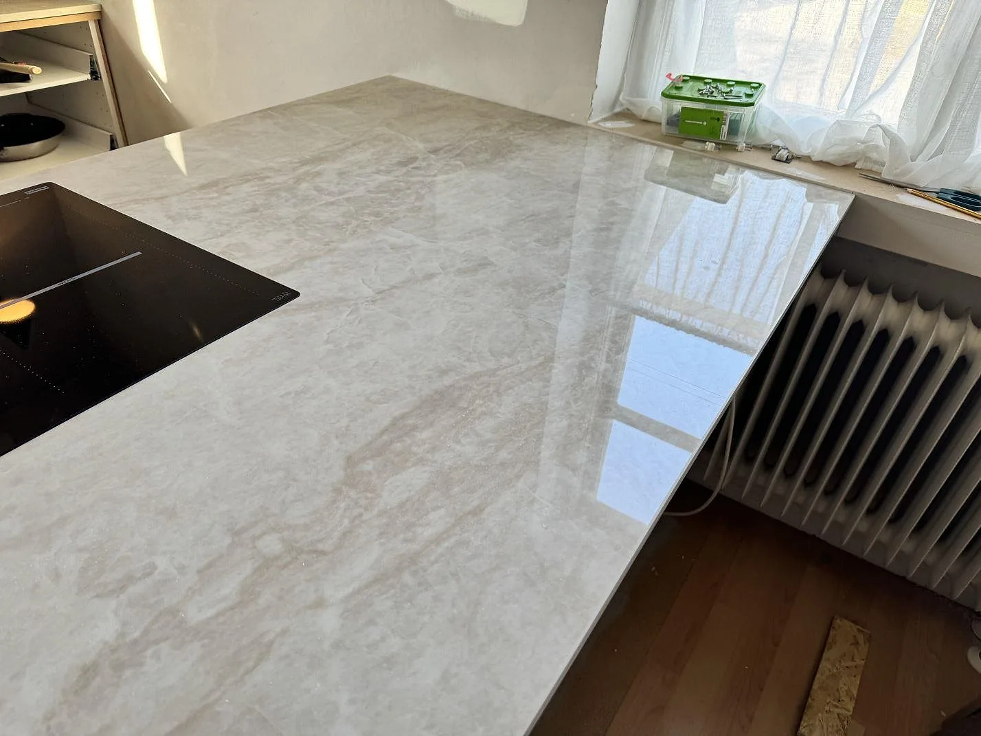 Polerad Dekton Arga på köksö med ljus ådring, svart häll och fönsterljus i ett kök i Svedala.