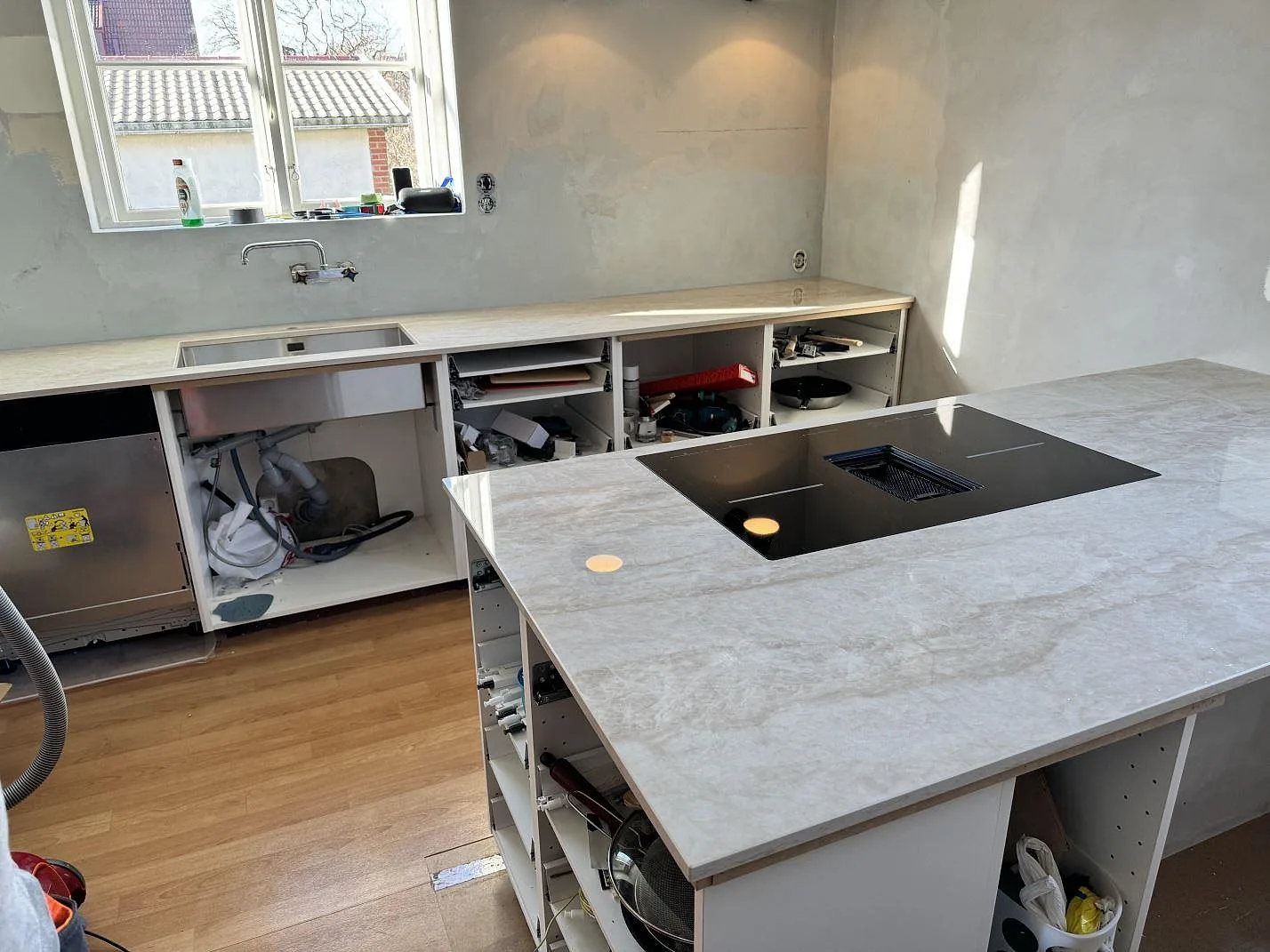 Köksö och köksbänkskiva i polerad Dekton Arga, 20 mm, med svart häll, rostfri diskho och öppna köksstommar i Svedala.