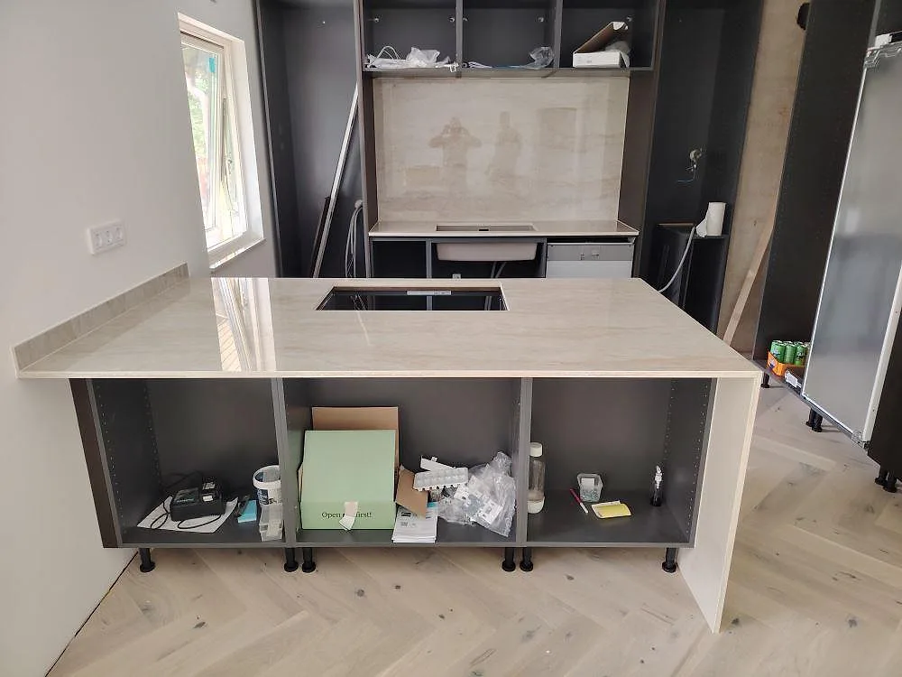 Köksbänkskiva och köksö i polerad Dekton Arga, 20 mm keramik, med hällöppning och stänkskydd i ett kök i Täby.