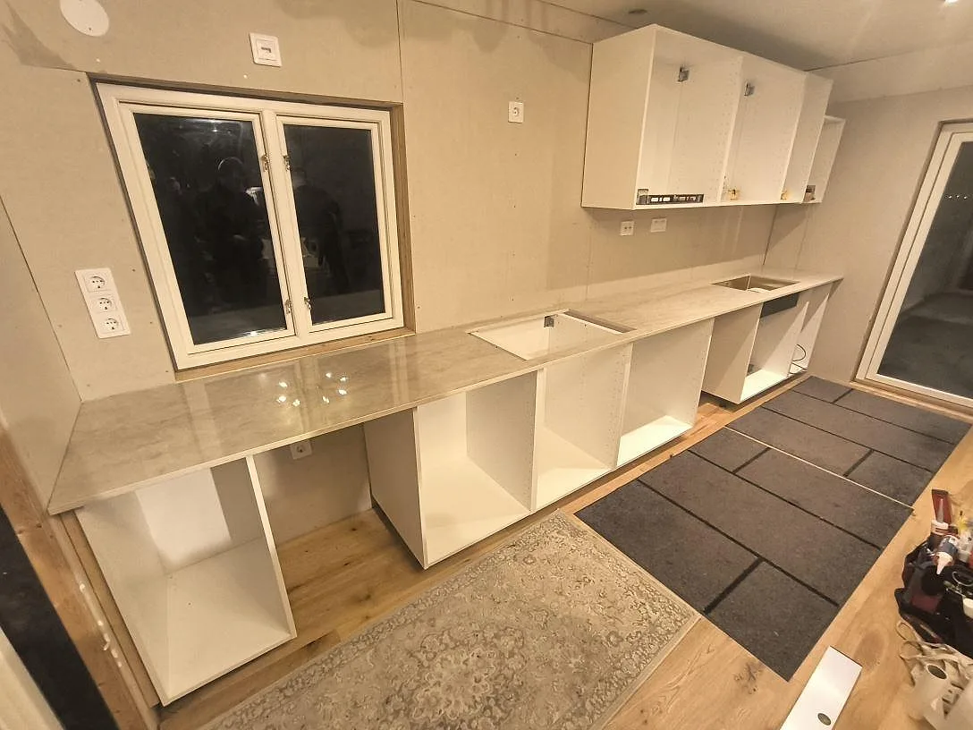 Köksbänkskiva i polerad Dekton Arga, 20 mm, monterad på vita köksstommar i Torsåker.