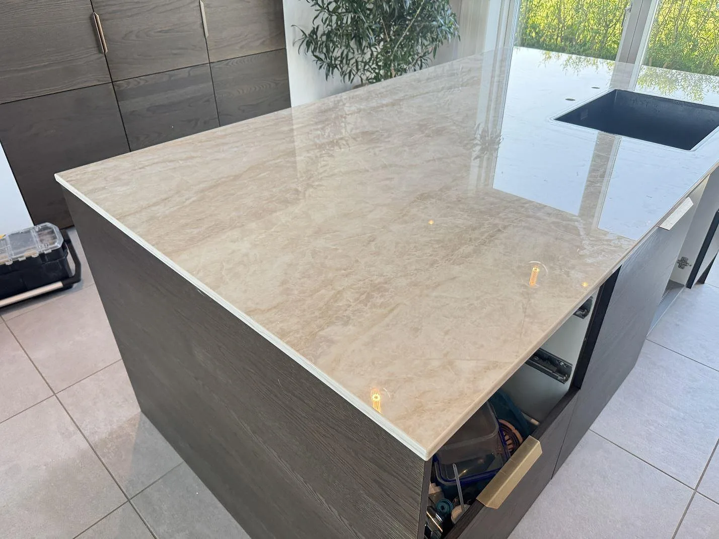 Köksbänkskiva i polerad Dekton Arga på köksö med svart diskho och ljus ådring i ett kök i Trige.