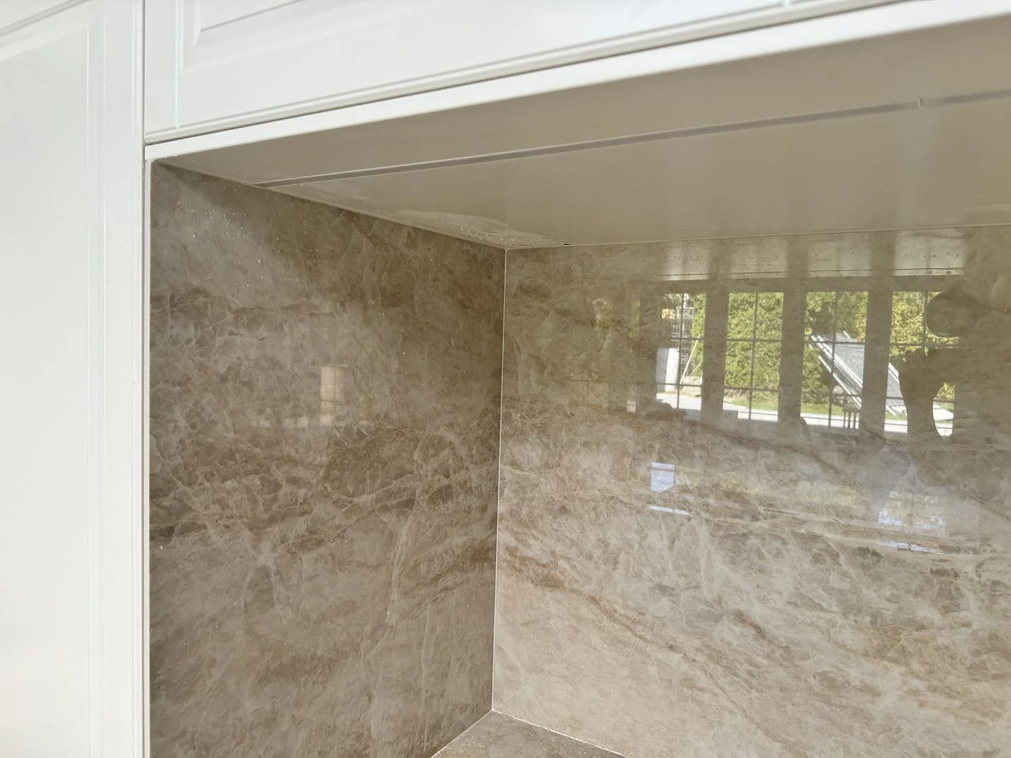 Detaljbild av polerad Dekton Arga som blank väggbeklädnad och köksbänkskiva i Tygelsjö.