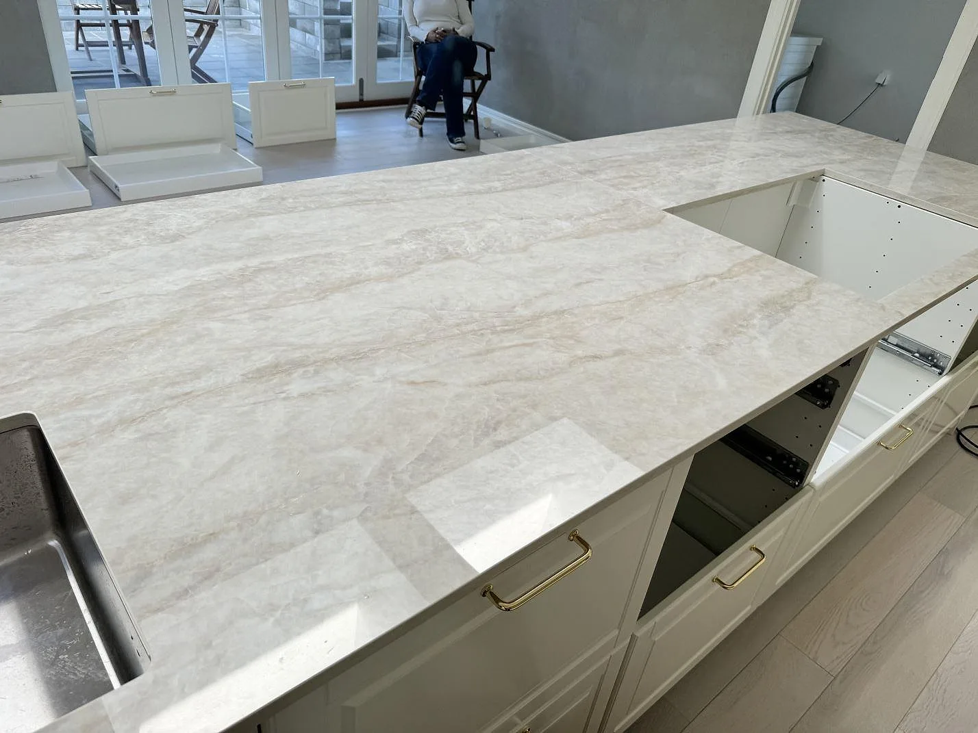 Polerad köksbänkskiva i Dekton Arga, keramik, med diskho och hällöppning i ett vitt kök i Tygelsjö.