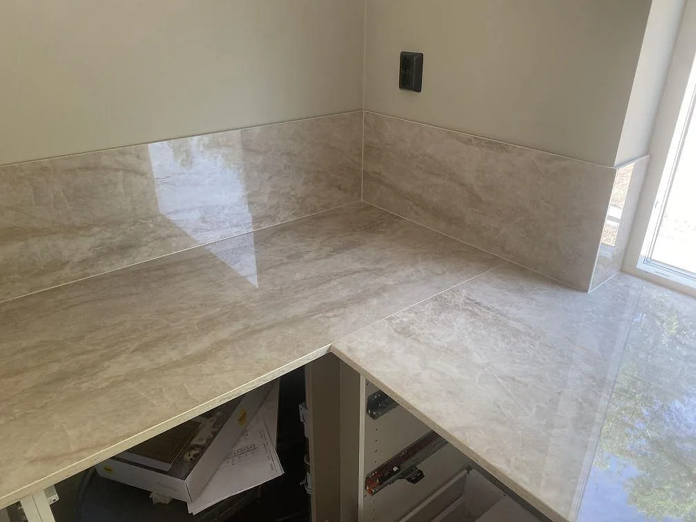 L-formad köksbänkskiva i polerad Dekton Arga med 8 mm stänkskydd och stora fönster i Uddevalla.
