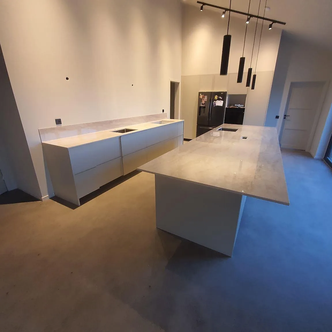 Kök i Uppsala med polerad Dekton Arga keramik på köksö och lång väggbänk med stänkskydd och urtag.